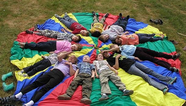 Jugendwerk - Kinder liegen auf einem Schwungtuch im Kreis